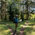 Man hiking in forest looking at map deciding which path to take